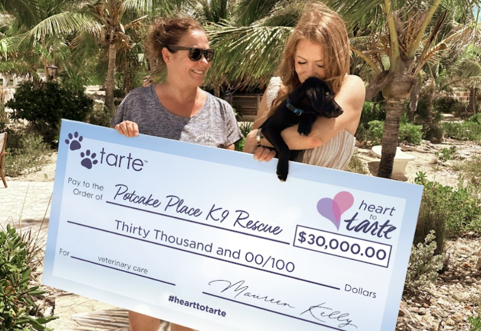 Maureen holding check for donation to Potcake Place k9 rescue